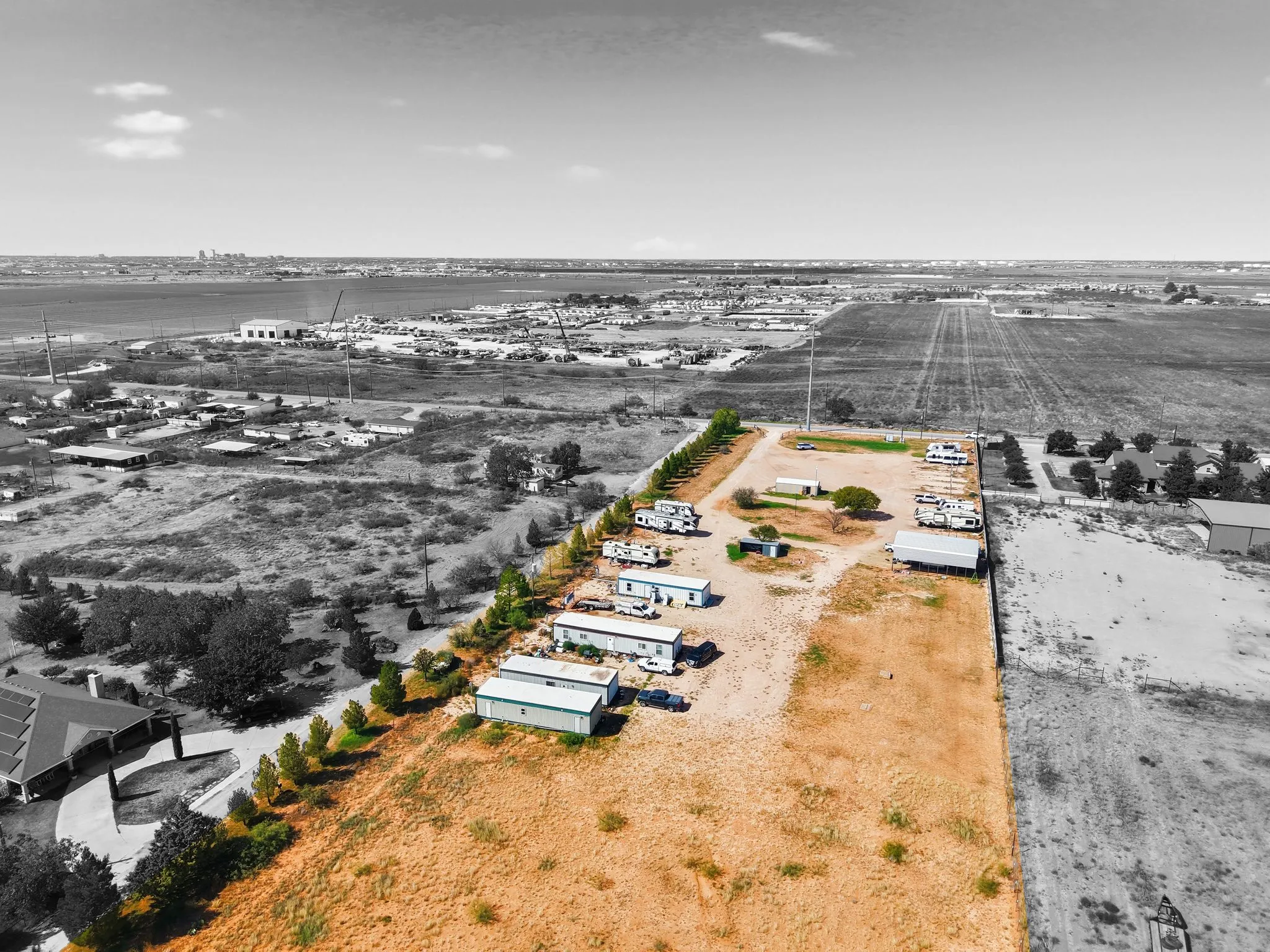 Aerial view of A1 RV Park: RVs, trailers, and work trucks along a caliche drive inside the fenced lot, with open Permian Basin land out to the horizon